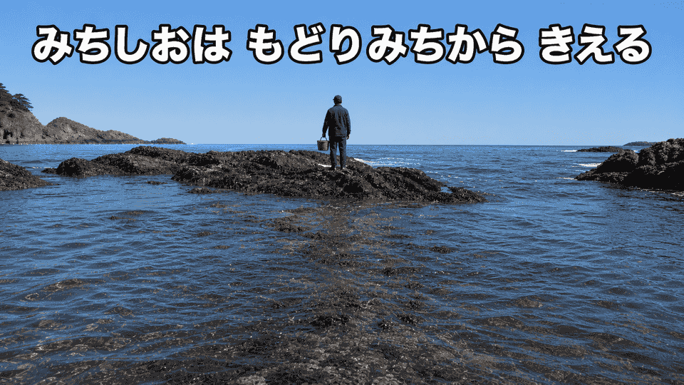 磯にいる人の背後で、満ち潮が岩伝いの戻り道へ回り込み、帰路が水に隠れ始める様子