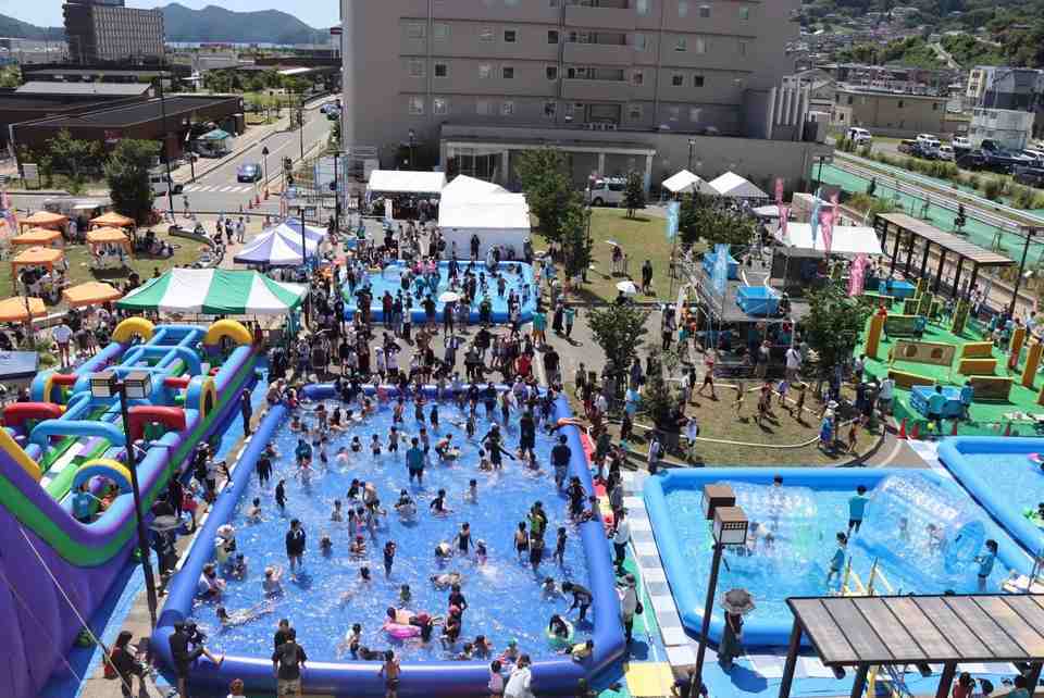 遊具とプールに来場者が集まる会場の俯瞰