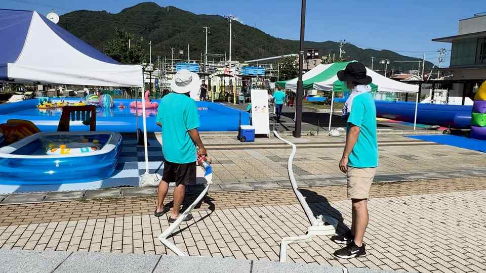 会場で白いホースを運ぶスタッフ